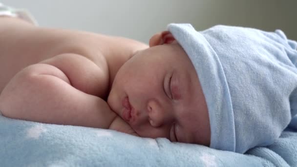 幼児期,小児期,開発,健康,愛,ケアの概念-トップビュー新生児の裸の睡眠のクローズアップ顔小さな赤ちゃんの男の子の帽子の上に横たわっ胃の上に柔らかい青の毛布の上に家でベッド — ストック動画