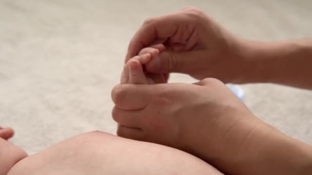 Догляд за шкірою здоров'я, педіатрія розвитку, малятка крупним планом руки дають оголеним новонародженим дитині масаж на руках, ногах, пальцях, рефлекс на ногах, натирання грудей живота на ліжку в домашніх умовах — стокове відео