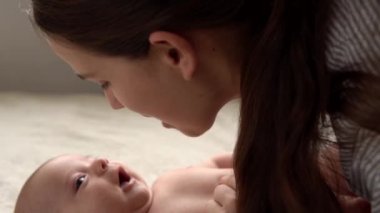 Otantik yakın çekim genç neo anne, doğum gününde beyaz yumuşak bir yatakta yeni doğmuş bebek bebekle oynuyor. Çocuk kavramı, ebeveynlik, çocukluk, hayat, annelik, annelik