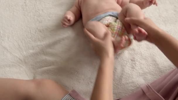 Health skin care, development pediatrics, infant close-up mother hands give naked newborn baby child massage on arms, legs, fingers, reflex on feet exercise, rubbing skin abdomen chest on bed at home — Stock Video