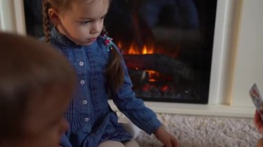 Çocukluk, eğitim, hobi, aile, arkadaşlar, arkadaşlık kavramı. Anne, anne, bebek bakıcısı ve anaokulu çocukları evde şöminenin yanında iskambil oynayarak vakit geçiriyorlar.