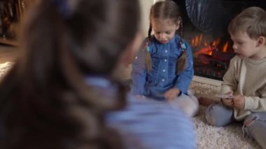 Çocukluk, eğitim, hobi, aile, arkadaşlar, arkadaşlık kavramı. Anne, anne, bebek bakıcısı ve anaokulu çocukları evde şöminenin yanında iskambil oynayarak vakit geçiriyorlar.