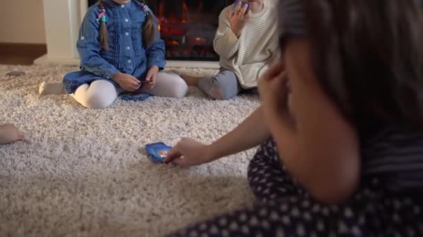 Dzieciństwo, edukacja, hobby, rodzina, przyjaciele, koncepcja przyjaźni. Szczęśliwa młoda matka mama opiekunka z małymi przedszkolakami dzieci spędzają czas grając w karty na podłodze w domu przy kominku — Wideo stockowe