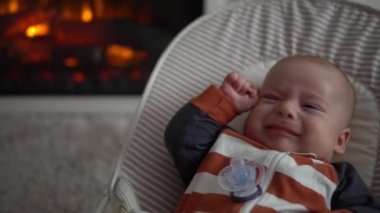 Kameradaki bebeğe bakmak, çocukluk, aile sevgisi. Çizgili elbiseli şirin gülen yüz uyandı. Evdeki şöminenin yanındaki sandalyeye uzandı. Neşeli yaşam tarzı mutlu çocuk.