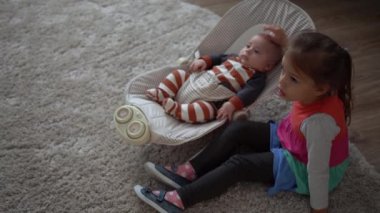 Çocukluk, annelik, aile, rahatlık. Çizgili pijamalı yeni doğmuş küçük bebek uyandı. Etrafa bakıp gülüyor. Kardeş kardeş gibi davranıyor.