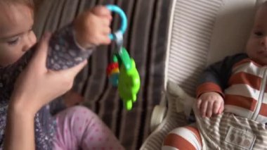 Çocukluk, annelik, aile, rahatlık. Çizgili pijamalı yeni doğmuş küçük bebek uyanmış etrafa bakıp gülüyor. Çıngıraklı yılanlarla oynuyor.