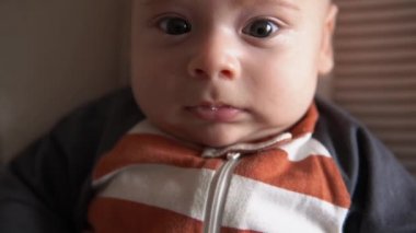 Kameradaki bebeğe bak. Bebek, çocukluk, aile sevgisi. Çizgili vücut pijamalarıyla doğan tatlı gülümseyen gözler uyandı ve evdeki yumuşak sandalyeye uzandı. Mutlu çocuğun neşeli yaşam tarzı