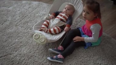 Çocukluk, annelik, aile, rahatlık. Çizgili pijamalı yeni doğmuş küçük bebek uyandı. Etrafa bakıp gülüyor. Kardeş kardeş gibi davranıyor.