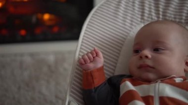 Kameradaki bebeğe bakmak, çocukluk, aile sevgisi. Çizgili elbiseli şirin gülen yüz uyandı. Evdeki şöminenin yanındaki sandalyeye uzandı. Neşeli yaşam tarzı mutlu çocuk.