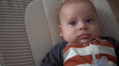 Kameradaki bebeğe bakmak, çocukluk, aile sevgisi. Çizgili elbiseli şirin gülen yüz uyandı. Evdeki şöminenin yanındaki sandalyeye uzandı. Neşeli yaşam tarzı mutlu çocuk.