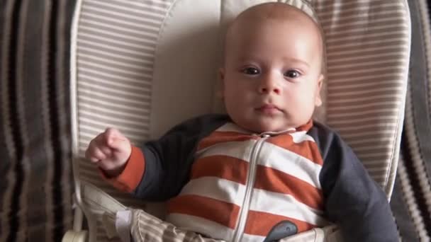 Enfance, maternité, famille, confort. Petit garçon nouveau-né en pyjama à rayures body éveillé regarde tout autour des sourires joue avec hochets reconnaît largement maman dans la chambre à la maison atmosphère — Video