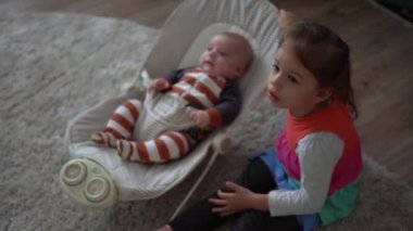 Çocukluk, annelik, aile, rahatlık. Çizgili pijamalı yeni doğmuş küçük bebek uyandı. Etrafa bakıp gülüyor. Kardeş kardeş gibi davranıyor.