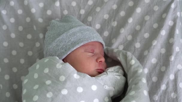 Recién nacido bebé rojo lindo retrato de la cara los primeros días durmiendo en la cama de vidrio médico sobre fondo gris. Niño al principio Minutos de vida en el sombrero. Bebés, Parto, Primeros Momentos Del Nacimiento, Principio Concepto — Vídeo de stock
