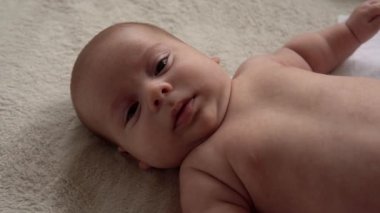Çocukluk, annelik, aile, hijyen, bebek konsepti yakın plan mutlu çocuk 2 aylık yeni doğan çocuk banyo sonrası beyaz yumuşak yatakta kameraya bakıyor. Bebek yatmadan önce uyanma zamanı.