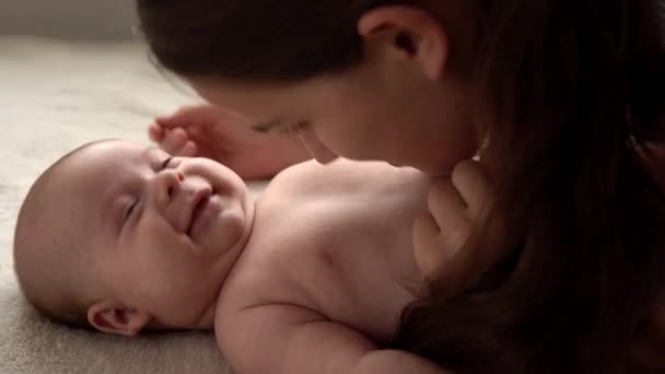 Autêntico close-up tiro jovem neo mãe mãe está brincando com nake bebê recém-nascido na cama macia branca no dia da manhã do berçário. Conceito de filhos, paternidade, infância, vida, maternidade, maternidade — Vídeo de Stock