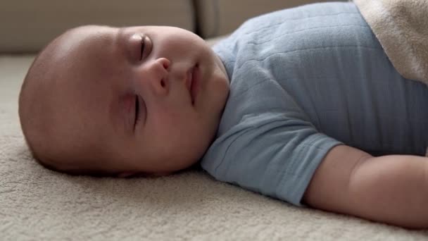 クローズアップサイドビュー面白いかわいい子供2ヶ月新生児は、白い柔らかいベッドでバスシャワーの後に眠りに落ちます.ベッドタイム前の赤ん坊の子供の目覚め時間コピースペース。子供時代,母親,家族,幼児の概念 — ストック動画