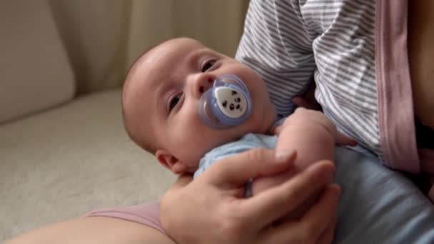 Keibuan, masa kecil, keluarga, perawatan, kesehatan, persalinan - bayi yang baru lahir dengan dot pakaian biru tidur di lengan ibu. Mum santai memegang memeluk bayi bayi bayi bayi di tempat tidur di rumah — Stok Video