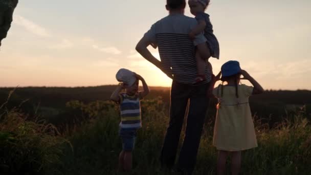 People in park. happy family walk at field. dad with many children on top of mountain in tall grass before sunset. parents and fun kids look into the distance. summer, fatherhood, childhood concept — Stock Video