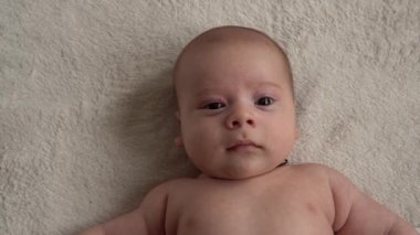 Çocukluk, annelik, aile, hijyen, bebek konsepti yakın plan mutlu çocuk 2 aylık yeni doğan çocuk banyo sonrası beyaz yumuşak yatakta kameraya bakıyor. Bebek yatmadan önce uyanma zamanı.