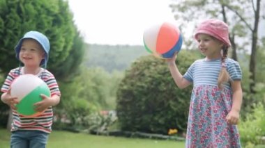 Çok Renkli Plaj Balosu 'yla koşan Mutlu Çocuklar. Oğlan ve Kız Çocuk, Sunny Summer Day 'de Idyllic Banliyö Evinin arka bahçesinde oyun oynuyorlar. Çocukluk, aile kavramı