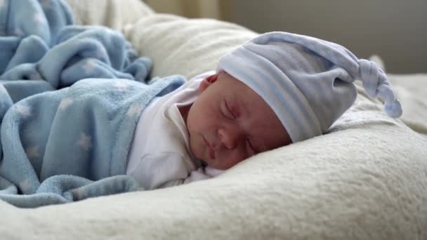 Yakın plan Yeni Doğmuş Bebek Yüzü İlk Günler Mavi Göbek Arkaplanında Tatlı Uyuyan Bebek Portresi. Hayata Başlayan Çocuk Şapka 'da. Bebekler, Doğum, Doğumun İlk Anları, Başlangıç Konsepti — Stok video