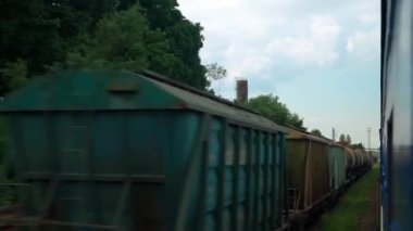 Terk edilmiş eski istasyon ve paslı yük vagonlarının penceresinden manzarası güneşli yaz günlerinde tren rayları. Ulaşım, seyahat, demiryolu, iletişim konsepti