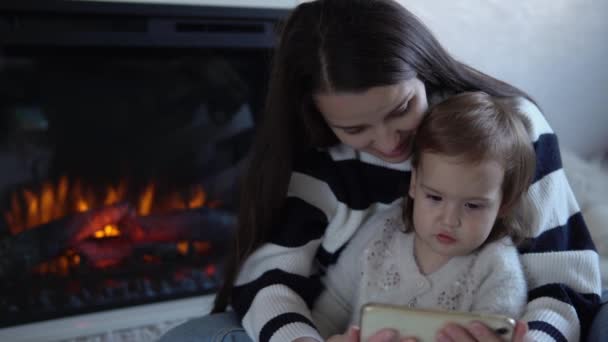 Brincalhão adorável criança criança filha gosta de aprender usando telefone inteligente com controle parental. Feliz família jovem mãe mãe mãe mãe mostrando engraçado cartoon aplicativo móvel, assistindo a vídeos relaxantes em casa — Vídeo de Stock