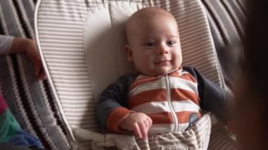 Omuz omuza. Çocukluk, annelik, aile. Çizgili pijamalı yeni doğmuş bebek uyanmış etrafa bakıyor gülümseyen oyunlar oynuyor annemi evde tanıdı.