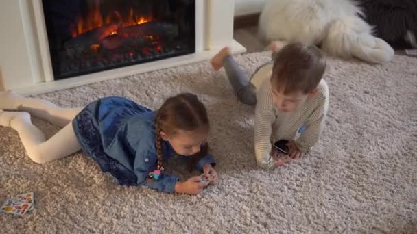 Kindheit, Bildung, Isolation. Erholsame Erholung zu Hause. Drei kleine pfiffige Vorschulkinder spielen Karten auf dem Teppichboden. Kinder Bruder Schwester Freunde haben Interesse an Glücksspielen — Stockvideo