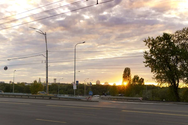 Summer, heat, travel, weather, cityscape - background wide paved roadway road with city cars in spring hot evening at sunset, summertime sunrise grey cloudy sky — Stock Photo, Image