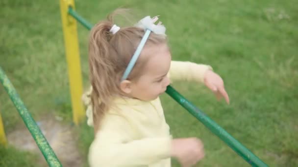 Söta förskolebarn på lekplatsen. Liten flicka rolig gör övningar på gymnastikbarer skrattar ha kul, svänger på gungbräda spela. Lycklig barndom, positiva känslor, POV koncept — Stockvideo