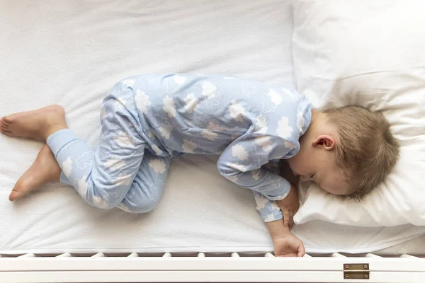 Top view Aranyos kis 2-3 éves óvodás fiú gyerek alszik édesen fehér bölcsőben ebédidő alatt pihenő kék pizsamában párnával otthon. Gyermekkor, szabadidő, kényelem, orvostudomány, egészség fogalma — Stock Fotó