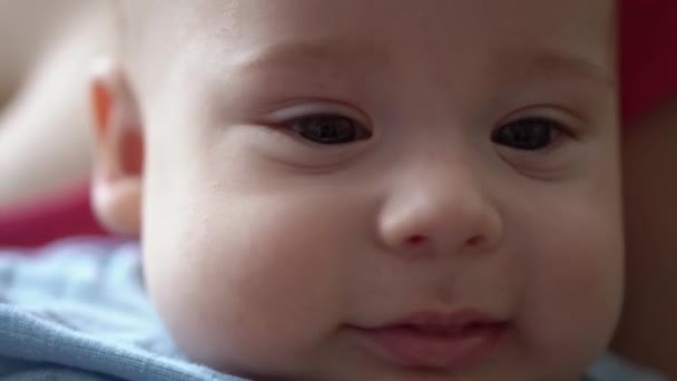 幼年时期新生儿的近视微笑会使人目瞪口呆。穿着蓝色紧身衣的梦后婴儿的鬼脸。《儿童在人生的第一分钟》 ， 《宏观中的肖像》。童年、幼儿概念 — 图库视频影像