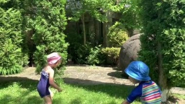 Sevimli mutlu çocuk, okul öncesi bebek ve oğlan çocuk dışarıda su pompalı tüfekle eğleniyor. Parkta güneşli sıcak bir gün. Çocuk Bahçesi Oyunları. Yaz, Spor, Tatil, Aile, Çocukluk