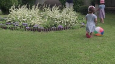 Mutlu Çocuklar çok renkli plaj balosu ve sabun köpükleriyle koşuyor. Anne, kız ve oğul yaz günü Idyllic Banliyö Evinin arka bahçesinde oyun oynuyorlar. Çocukluk, aile kavramı