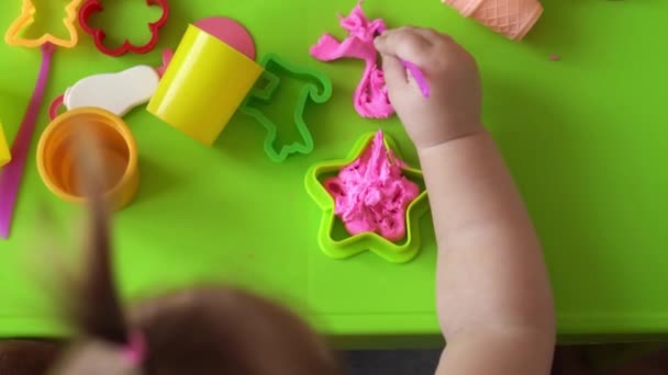 Bildhauerei und Modellierung aus Ton für Kinder. Mädchen im Alter von 2-5 Jahren formen und formen rosa Spielteig mit Fingern und Modelliermesser aus Kunststoff. Feinmotorik und Kreativität der Kinder mit Spielknete fördern — Stockvideo