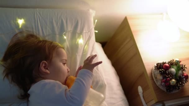 Jovem mãe alimentando nutrição leite materno para a pequena menina de mamadeira deitada na cama no dormitório à noite. Mulher toque bebê recém-nascido bonito suavemente e quente. Mãe cuidar criança com o conceito de cuidado de amor — Vídeo de Stock