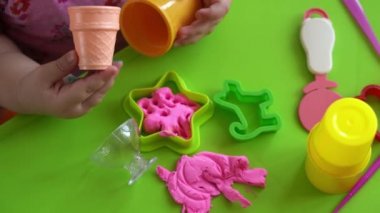Çocuklar için heykel ve kil modelleme. 2-5 yaşlarındaki kız pembe oyun hamurunu parmaklarıyla ve plastik maket bıçağıyla şekillendiriyor. Oyun kilini kullanarak iyi motor becerileri ve çocuk yaratıcılığını geliştirmek.