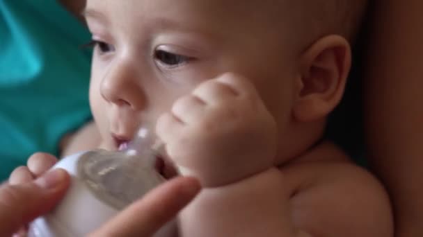 家庭母亲，人们。关闭快乐的母亲的小宝宝在家里带着奶瓶的水奶嘴。年轻妈妈铣削新生儿看着相机，疼痛儿科医疗 — 图库视频影像