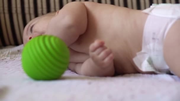 Οικογένεια, παιδική ηλικία. Κοντινό πλάνο Happy baby baby with Teething Toy. Γυμνό μικρό παιδί σε πάνα παίζει πράσινο καουτσούκ μπάλα Roll πάνω στο στομάχι στο σπίτι. Νεογνό παιδί Υγείας μασάζ ιατρικής — Αρχείο Βίντεο