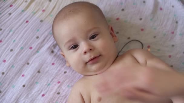 Malá nahá plenka novorozeně dítě je legrační úsměv, ležící na zádech. Portrét šťastné hravé energické dítě kousání prsty nohy masáž medicína pediatrie dělá jednoduché cvičení kosti svaly silnější — Stock video
