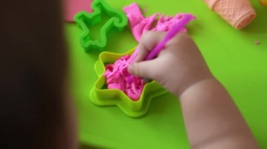 Çocuklar için heykel ve kil modelleme. 2-5 yaşlarındaki kız pembe oyun hamurunu parmaklarıyla ve plastik maket bıçağıyla şekillendiriyor. Oyun kilini kullanarak iyi motor becerileri ve çocuk yaratıcılığını geliştirmek.