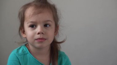 Portre. Kameraya bakan komik küçük kız. Evdeki kanepede oturuyor. Güzel yüzlü şirin çocuk.