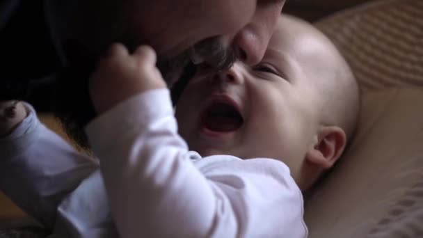 Filmisk exstra närbild av unga skäggiga Happy neo far leker kyss med nyfödda barn son leende i barnkammaren morgon. Begreppsbarn, föräldraskap, barndom, liv, kärlek, faderskap, familj — Stockvideo