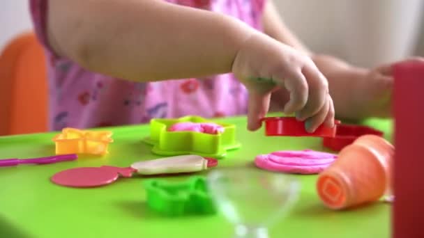 어린이들을 위한 조각 과 점토 모형. 2-5 살 여자 아이가 손가락 과 플라스틱 모형 칼로 분홍색 점토를 만들고 모양을 만들었습니다. 점토를 사용하여 훌륭 한 운동 기술 과 아이들의 창의력을 향상시키는 일 — 비디오