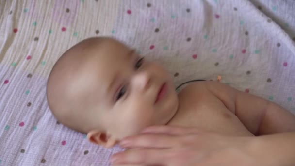 Kleine Naakte luier pasgeboren baby is grappig lachend, liggend achterin. Portret van vrolijk speels energiek kind bijtende tenen voeten massage geneeskunde pediatrie doen eenvoudige oefening botten spieren sterker — Stockvideo