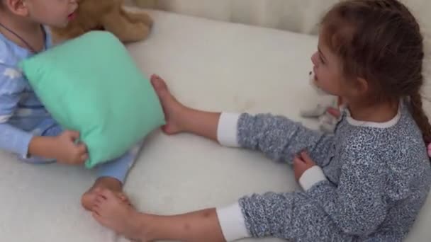 Two Smiling Preschool Toddler Children In Pajamas Playing With Teddy Bear on Bed. Siblings Little Twins Boy and Girl Have Fun. Happy Kids On Quarantine At Home. Friendship, Family, Education Concept — Stock Video