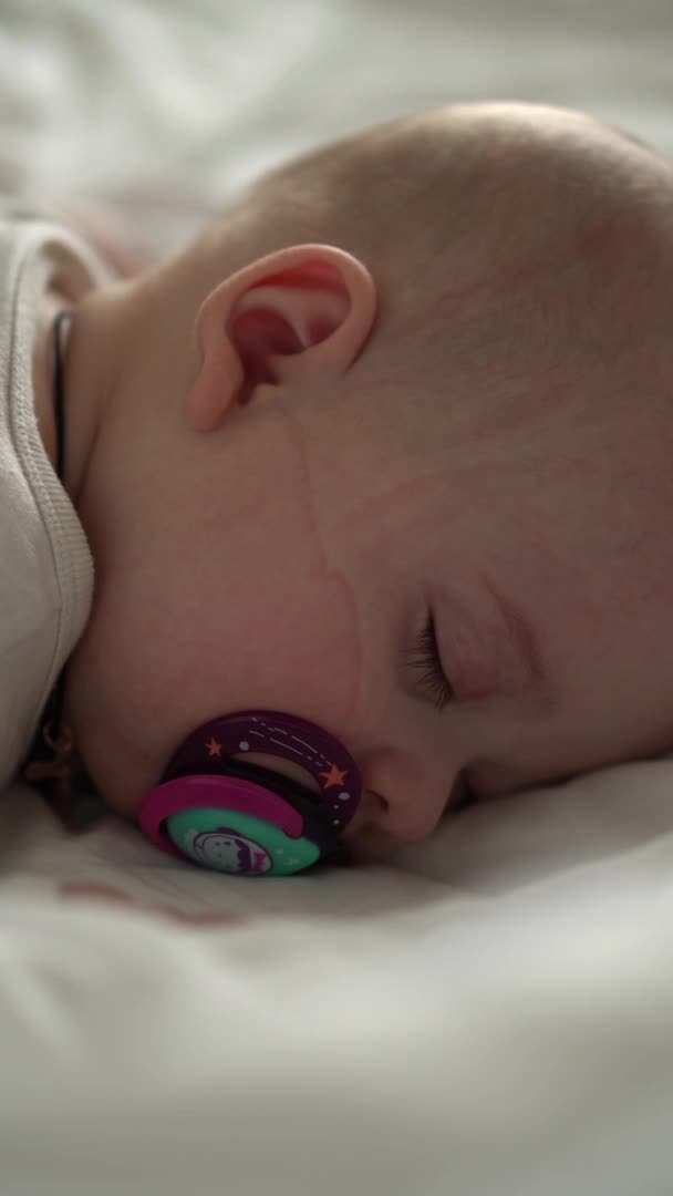 Vertikální detailní tvář novorozeně baculaté spící dítě ležící na břiše otevřené oči a úsměv pokrytý přikrývkou na posteli na bílém pozadí. kojenectví, dětství, vývoj, medicína a zdravotní koncepce. — Stock video