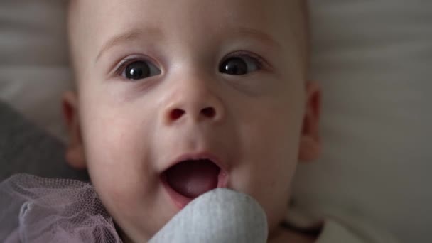 Detailní záběr Šťastné hravé dítě 6 měsíců staré. Novorozený chlapec se dívá na kameru po koupeli sprcha na bílé měkké posteli. Dítě se probouzí před spaním s hračkou. Dětství, mateřství, rodina, kojenecká koncepce — Stock video