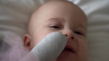 Yakın plan Mutlu neşeli çocuk 6 aylık. Yeni doğan çocuk, beyaz yumuşak yatakta banyo sonrası kameraya bakıyor. Bebek oyuncakla yatmadan önce uyandı. Çocukluk, annelik, aile, bebek konsepti